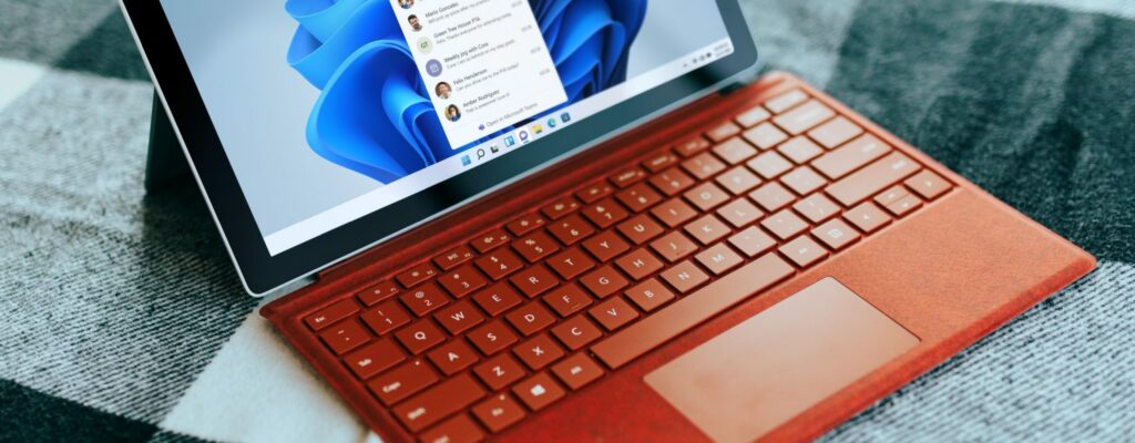 Red Surface laptop on a checkered bed by a window